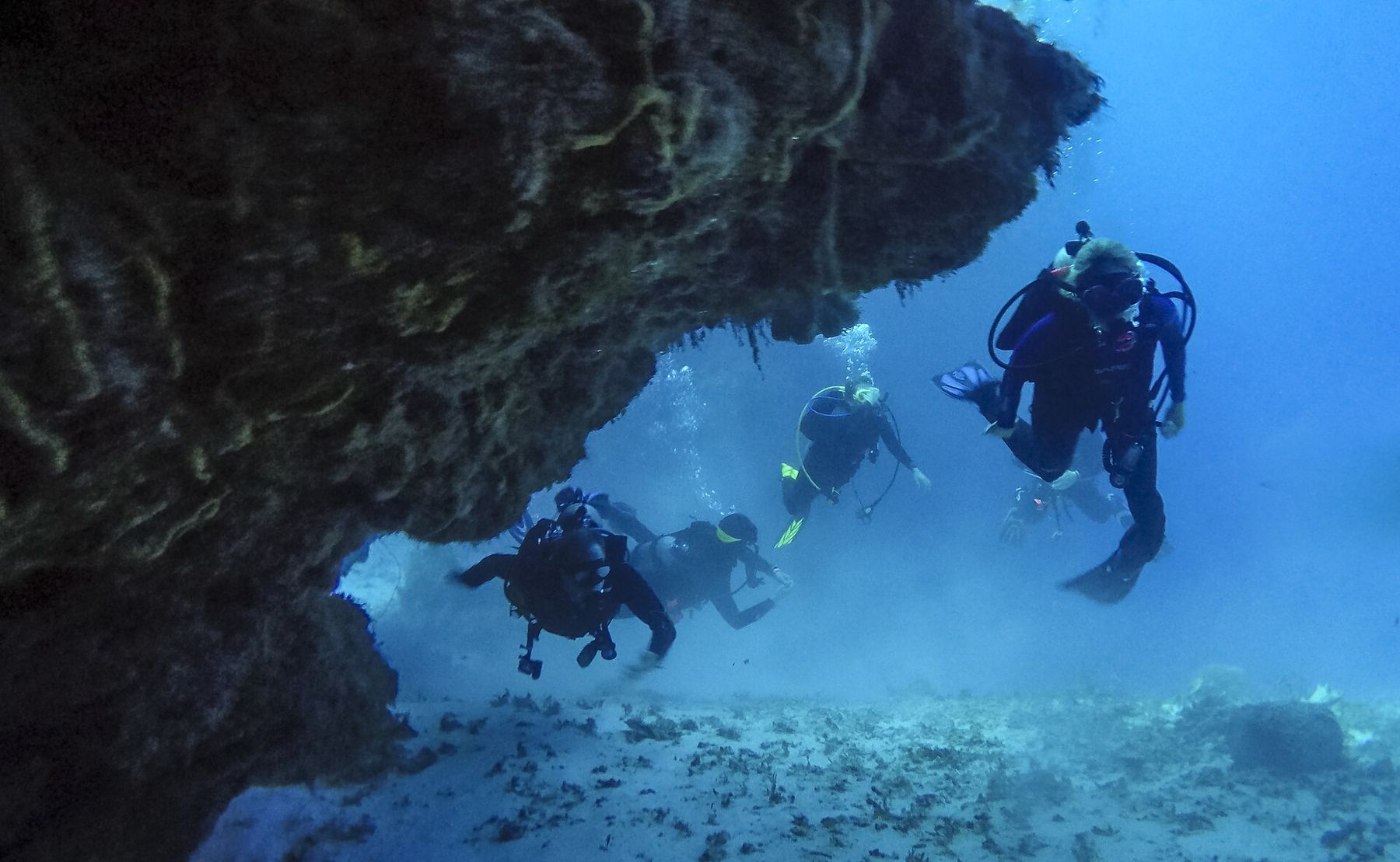 Scuba divers swimming through a coral swim-through in Cozumel